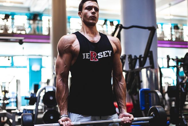 Muscular man lifting barbell in gym